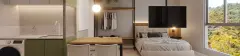 Studio com cozinha verde, mesa de jantar, closet aberto e cama de casal com TV e vista para árvores — Adore Canasvieiras em Canasvieiras, Florianópolis