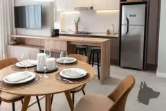 Sala de jantar integrada à cozinha americana com mesa redonda, balcão e geladeira — Adore Canasvieiras em Canasvieiras, Florianópolis