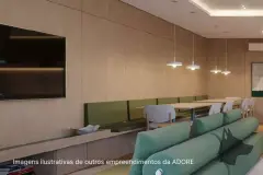Sala lounge com sofás verdes, mesa longa e TV embutida em painel de madeira — Adore Smart Nova Cachoeira em Cachoeira do Bom Jesus, Florianópolis