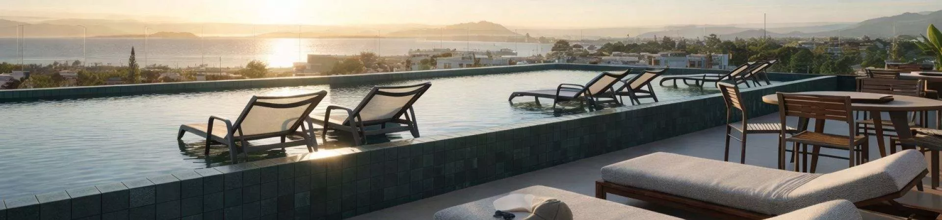Perspectiva ilustrativa da piscina de borda infinita no rooftop ao pôr do sol com espreguiçadeiras dentro d'água e vista panorâmica para o mar de Cachoeira do Bom Jesus — Algae Beach Residence em Cachoeira do Bom Jesus, Florianópolis