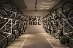Perspectiva ilustrativa do bicicletário com suportes empilhados dos dois lados e frase motivacional na parede — Algae Beach Residence em Cachoeira do Bom Jesus, Florianópolis