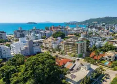 Vista aérea real do edifício Almare Jurerê destacado em meio ao bairro com o mar e as ilhas ao fundo — Almare Jurerê em Jurerê, Florianópolis