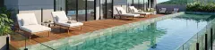 Piscina de borda infinita panorâmica com deck de madeira, espreguiçadeiras brancas e vista para os morros de Jurerê — Almare Jurerê em Jurerê, Florianópolis