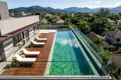 Piscina de borda infinita real com espreguiçadeiras brancas, deck de madeira e vista panorâmica para os morros de Jurerê — Almare Jurerê em Jurerê, Florianópolis
