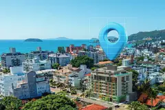 Vista panorâmica da piscina de borda infinita com espreguiçadeiras, deck de madeira e morros e palmeiras ao fundo — Almare Jurerê em Jurerê, Florianópolis