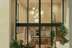 Sala do duplex vista do andar superior com pendentes esféricos, sofá branco, poltrona Eames e escada de vidro — Almare Jurerê em Jurerê, Florianópolis