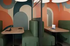 Coworking com cabines privativas em estofado verde e paredes com murais coloridos de formas geométricas — Alto Montreal em Trindade, Florianópolis
