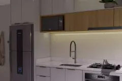 Perspectiva ilustrativa da cozinha com armários brancos e madeira, geladeira, pia e cooktop com iluminação LED sob bancada — Aquamarina Residence em Cachoeira do Bom Jesus, Florianópolis