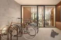Perspectiva do bike parking com três bicicletas em suporte de madeira, letreiro Bike Parking e porta envidraçada para o lobby — Art Blue View em Jurerê, Florianópolis