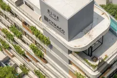 Foto aérea real do topo do Art Blue View com cobertura curva, varandas com vegetação, caixas d'água e logotipos Blue Concept e Cymaco — Art Blue View em Jurerê, Florianópolis