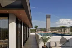 Perspectiva do terraço de lazer com piscina, passarela lateral, sofá externo, palmeira e torre técnica ao fundo — Arts Home Design em Ingleses, Florianópolis