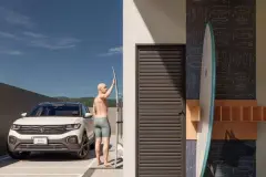 Perspectiva da garagem com ducha de surf ao ar livre, prancha apoiada, carro SUV e armário de esportes com revestimento temático — Arts Home Design em Ingleses, Florianópolis