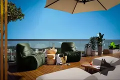 Perspectiva do terraço privativo com poltronas de couro verde, mesa lateral de madeira, guarda-sol e vista para a praia de Jurerê — At One Jurerê Studios em Jurerê, Florianópolis