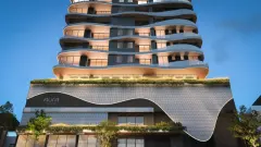 Perspectiva da fachada do Aura Residence ao entardecer em close com varandas onduladas iluminadas, logotipo Aura e lojas térreas com jardim suspenso — Aura em Agronômica, Florianópolis
