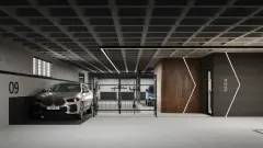 Perspectiva da garagem subterrânea com vaga 09, suporte suspenso para bicicletas, carro BMW e acesso ao hall com painel de madeira iluminado — Aura em Agronômica, Florianópolis