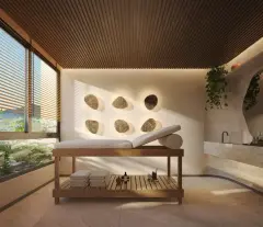 Perspectiva da sala de massagem com maca de madeira, parede com seixos decorativos embutidos, teto de ripas e janela com vista — Aura em Agronômica, Florianópolis