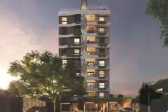 Perspectiva da fachada do Aura Residence Capoeiras ao entardecer iluminada, painel de folhas em relevo, varandas com vegetação e loja térrea — Aura Residence em Capoeiras, Florianópolis