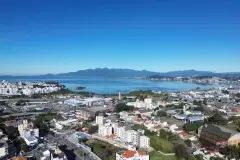 Foto aérea real com vista para a Baía Sul, morros, Capoeiras e São José com céu azul intenso, sem marcações — Aura Residence em Capoeiras, Florianópolis