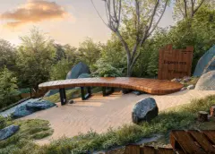 Perspectiva do Espaço Zen do B7 Essence Brava com deck de madeira sinuoso sobre areia branca, pedras e vegetação nativa ao entardecer — B7 Essence Brava em Praia Brava, Florianópolis