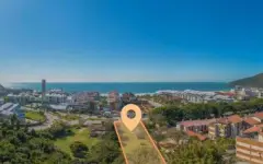 Foto aérea real de localização do B7 Essence Brava com pino marcador laranja e vista para a Praia Brava com edificações e oceano ao fundo — B7 Essence Brava em Praia Brava, Florianópolis