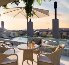 Perspectiva da piscina no rooftop do B7 Essence Brava com cadeiras de vime, guarda-sol e bóias flutuantes ao entardecer - ângulo alternativo — B7 Essence Brava em Praia Brava, Florianópolis