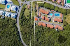 Foto aérea real do terreno do B7 Essence Brava delimitado em branco com vegetação nativa e bairro da Praia Brava ao redor — B7 Essence Brava em Praia Brava, Florianópolis