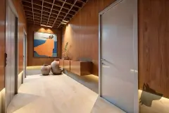 Perspectiva do corredor social do B7 Essence Brava com revestimento de madeira, iluminação indireta, vasos de cerâmica e obra de arte — B7 Essence Brava em Praia Brava, Florianópolis
