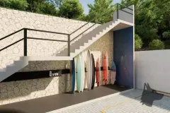 Perspectiva do surf storage do B7 Essence Brava com pranchas coloridas apoiadas em parede de pedra e escadaria de concreto — B7 Essence Brava em Praia Brava, Florianópolis