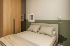 Perspectiva do quarto do apartamento do B7 Essence Brava com cama de solteiro, closet de madeira e meia parede em verde musgo — B7 Essence Brava em Praia Brava, Florianópolis
