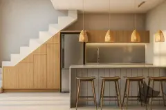 Perspectiva da cozinha do apartamento loft do B7 Essence Brava com ilha com banquetas, luminárias de vime e escadaria lateral — B7 Essence Brava em Praia Brava, Florianópolis
