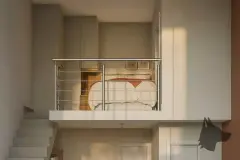 Perspectiva do mezanino do apartamento loft do B7 Essence Brava com cama de casal, guarda-roupa e guarda-corpo de aço inox — B7 Essence Brava em Praia Brava, Florianópolis