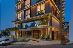 Perspectiva da fachada frontal do B7 Park Marina à noite com lojas iluminadas no térreo — B7 Park Marina em Agronômica, Florianópolis