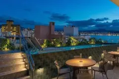 Perspectiva do rooftop do B7 Park Marina à noite com piscina e mesas com vista para a Baía de Florianópolis — B7 Park Marina em Agronômica, Florianópolis