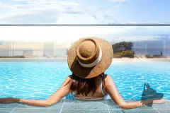 Foto de mulher com chapéu de palha relaxando na piscina do Barra 4 Club Residence com vista para a praia — Barra 4 Club Residence em Barra da Lagoa, Florianópolis