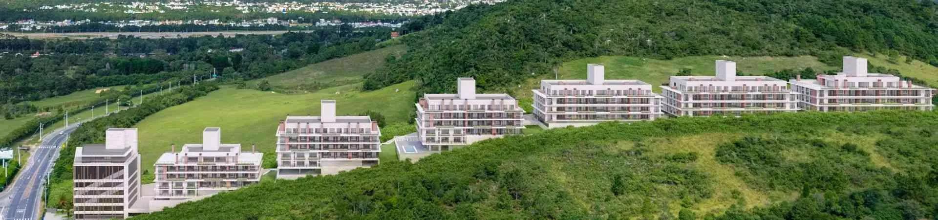 Vista aérea panorâmica das 6 torres do Bellomonte Residence em encosta verde com campo de golfe e cidade ao fundo — Bellomonte Residence em Ingleses, Florianópolis