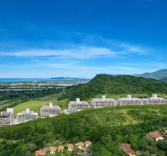 Vista aérea das torres do Bellomonte Residence em encosta verde com cidade e mar dos Ingleses ao fundo — Bellomonte Residence em Ingleses, Florianópolis