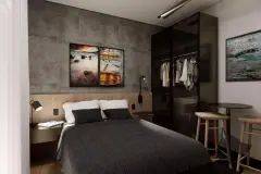 Dormitório estilo industrial com cama de casal, parede de cimento, guarda-roupa espelhado preto e mesa bistrô — Beriyth Residence em Cachoeira do Bom Jesus, Florianópolis