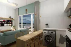 Sala de estar integrada à jantar, sofá azul claro, mesa de jantar em madeira e cozinha com máquina de lavar — Beriyth Residence em Cachoeira do Bom Jesus, Florianópolis