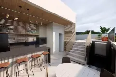 Rooftop com bancada bar, bancos altos em couro, churrasqueira e escada para área superior — Beriyth Residence em Cachoeira do Bom Jesus, Florianópolis