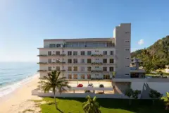 Dormitório com cama de casal, parede de cimento texturizado, quadros marinhos e janela com vista para o morro — Beriyth Residence em Cachoeira do Bom Jesus, Florianópolis