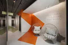 Hall de entrada com cadeiras bola cromadas, parede laranja e letreiro Bem Vindo / Welcome / Bienvenido — BG Connect Canas em Canasvieiras, Florianópolis