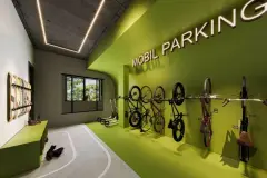 Bicicletário Mobil Parking com paredes verdes, suportes verticais para bicicletas e patinetes no chão — BG Connect Canas em Canasvieiras, Florianópolis