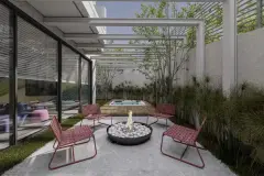 Área de lazer térrea com fire pit, cadeiras vermelhas, mesa de madeira, jardim e acesso à academia — BG Connect Trindade 2 em Trindade, Florianópolis
