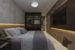 Dormitório com cama de casal, parede de cimento texturizado, closet com iluminação indireta e TV embutida — Bohn Residence em Ingleses, Florianópolis
