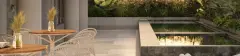 Área de lazer com piscina espelhada, deck em porcelanato, mesa bistrô e cadeiras de vime ao entardecer — Brio 778 em Estreito, Florianópolis