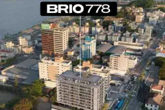 Vista aérea do Brio 778 no Estreito com logotipo, bairro e a Baía Sul de Florianópolis ao fundo — Brio 778 em Estreito, Florianópolis