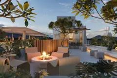 Rooftop ao entardecer com fire pit circular, poltronas, sofás e jardim com frangipanis iluminados — Brisa do Leste Residence em Barra da Lagoa, Florianópolis