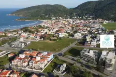 Vista aérea da Barra da Lagoa com praia, montanhas e terreno do Brisa do Leste Residence com logotipo — Brisa do Leste Residence em Barra da Lagoa, Florianópolis