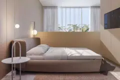 Suíte com cama estofada em caramelo, cabeceira alta, mesa lateral redonda e janela com planta monstera — Brisa do Leste Residence em Barra da Lagoa, Florianópolis