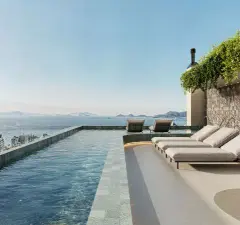 Piscina de borda no rooftop com espreguiçadeiras e mesa, vista para a Baía Sul e ilhas ao entardecer — Cais by Nova em Centro, Florianópolis